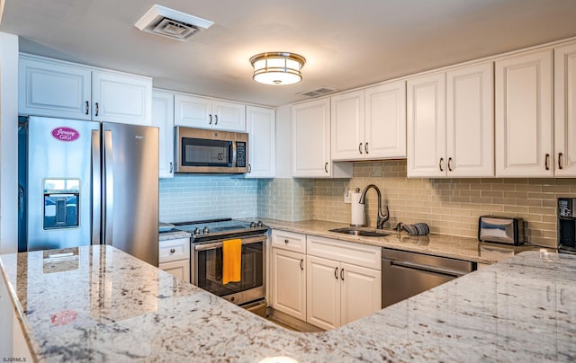 kitchen with white cabinetry, sink, light stone countertops, decorative backsplash, and appliances with stainless steel finishes