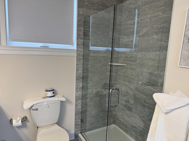 bathroom with a shower with shower door and toilet