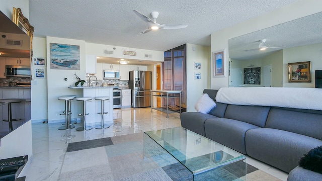 living room with ceiling fan and a textured ceiling