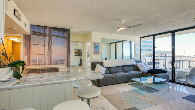 living room with a textured ceiling, a wall of windows, and ceiling fan