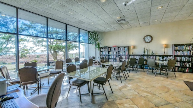 dining area featuring floor to ceiling windows, a paneled ceiling, and a high ceiling