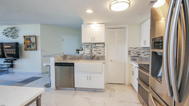 kitchen with backsplash, stainless steel appliances, white cabinetry, and sink