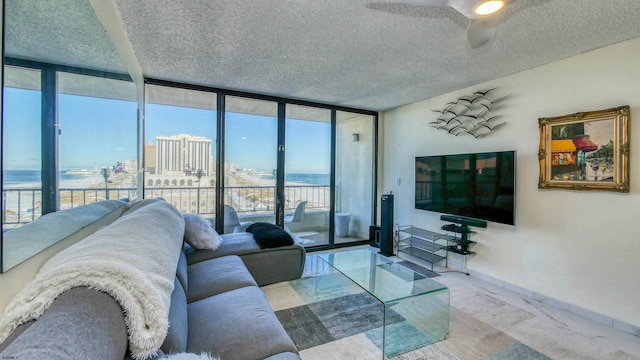 living room with a textured ceiling, a water view, a wall of windows, and ceiling fan