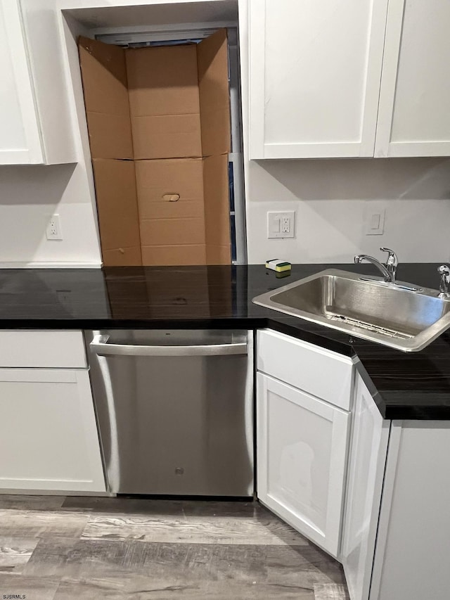 kitchen with stainless steel dishwasher, white cabinets, light wood-type flooring, and sink