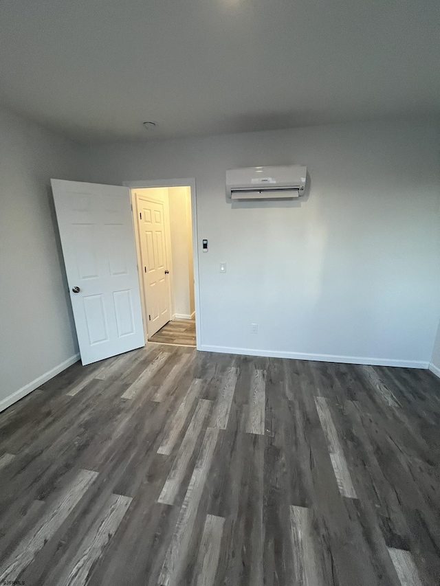 unfurnished room featuring a wall mounted air conditioner and dark wood-type flooring