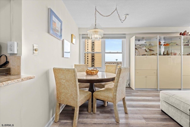 dining room with hardwood / wood-style floors, a textured ceiling, and an inviting chandelier