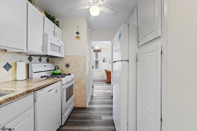 kitchen with white appliances, ceiling fan, dark hardwood / wood-style floors, light stone countertops, and white cabinetry