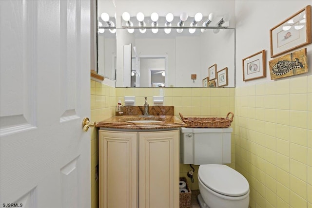 bathroom featuring vanity, toilet, and tile walls