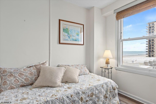 bedroom with hardwood / wood-style flooring and a water view