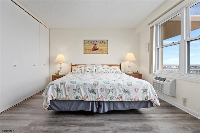 bedroom with a wall mounted air conditioner, hardwood / wood-style floors, and a closet