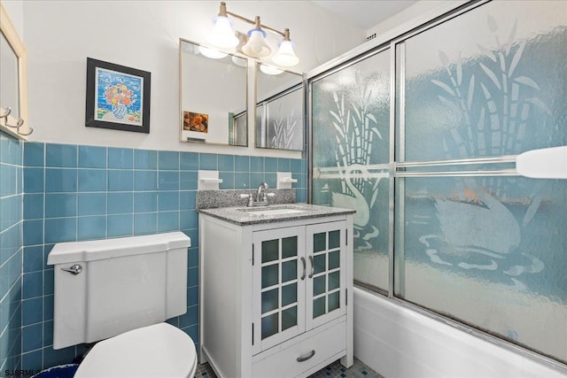 full bathroom featuring vanity, toilet, tile walls, and enclosed tub / shower combo