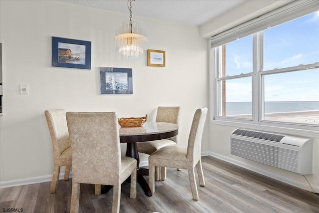 dining area featuring a water view, an inviting chandelier, plenty of natural light, and an AC wall unit