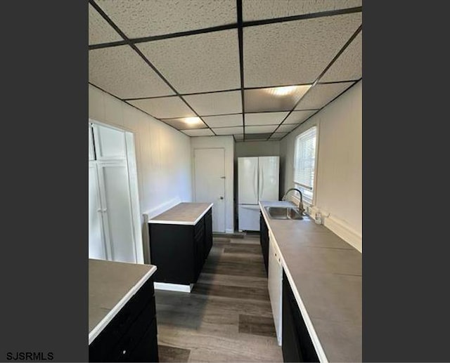 kitchen with white refrigerator, a drop ceiling, dark wood-type flooring, and sink