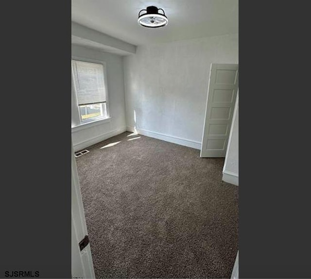 unfurnished room with dark carpet