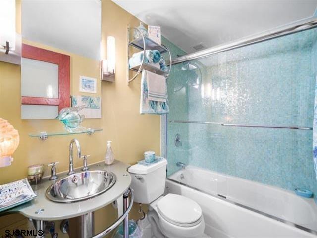 full bathroom with combined bath / shower with glass door, toilet, and sink