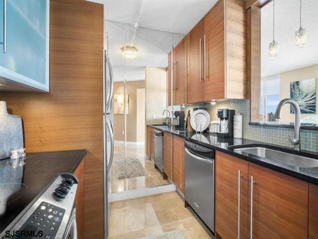 kitchen with dishwasher, sink, dark stone countertops, decorative light fixtures, and range