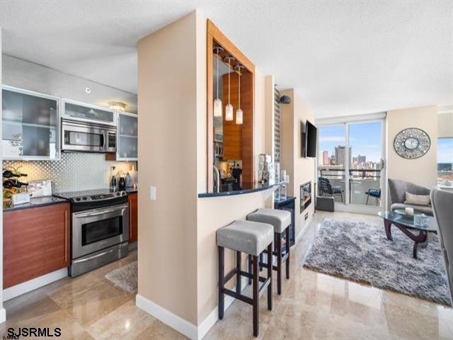 kitchen with a kitchen bar, a textured ceiling, appliances with stainless steel finishes, and tasteful backsplash