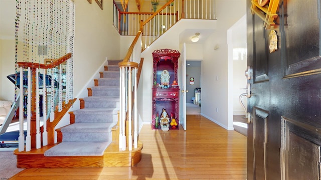 stairway with wood-type flooring and a towering ceiling