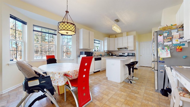 kitchen featuring appliances with stainless steel finishes, hanging light fixtures, a kitchen island, and white cabinets