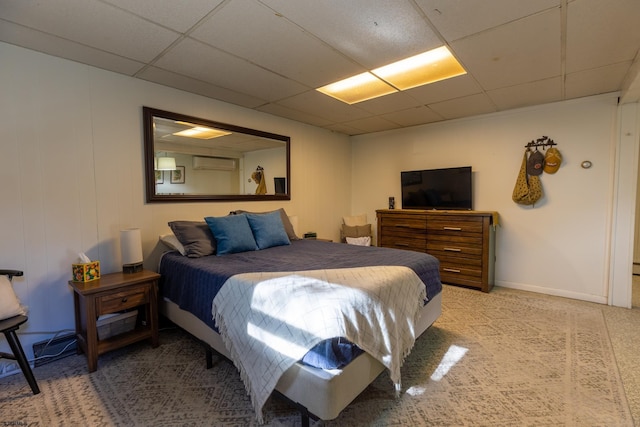 bedroom featuring a paneled ceiling, a wall unit AC, and baseboards