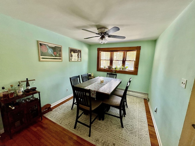 dining room with a ceiling fan, a baseboard radiator, baseboards, and wood finished floors