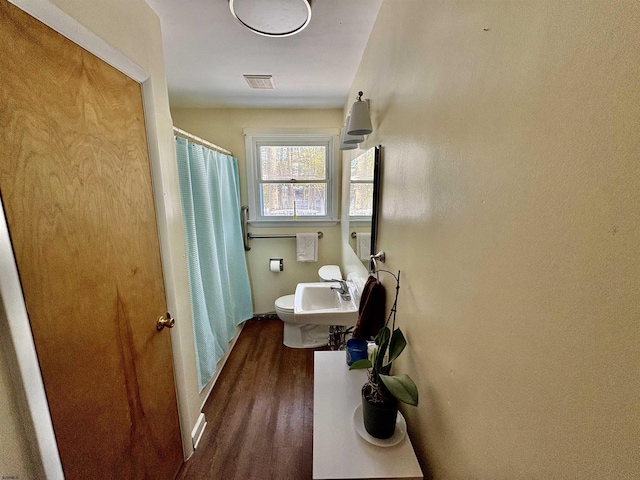 full bath with visible vents, toilet, wood finished floors, curtained shower, and a sink