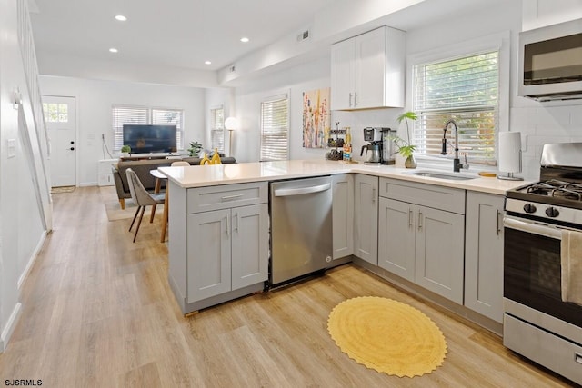 kitchen with kitchen peninsula, sink, gray cabinetry, and appliances with stainless steel finishes