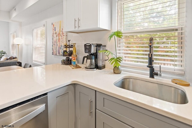 kitchen featuring dishwasher, backsplash, gray cabinetry, and sink