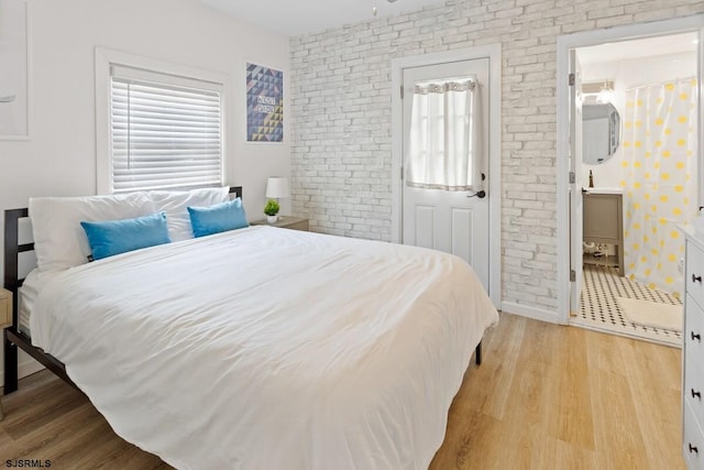 bedroom with light wood-type flooring and brick wall