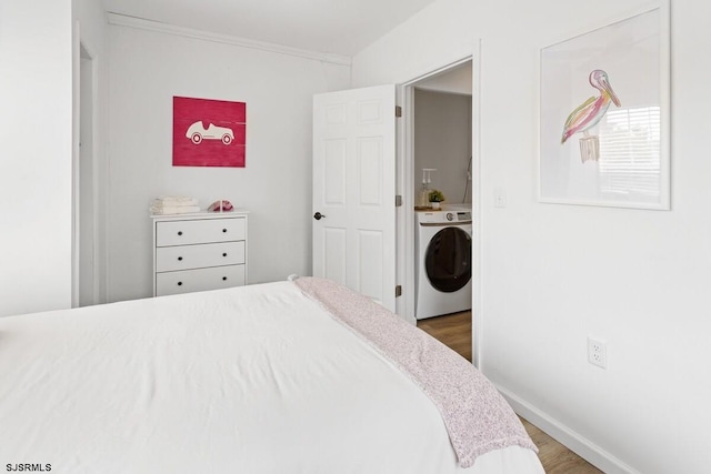 bedroom featuring dark hardwood / wood-style flooring, washer / clothes dryer, and crown molding