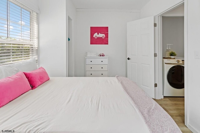 bedroom featuring hardwood / wood-style floors, washer / dryer, crown molding, and multiple windows