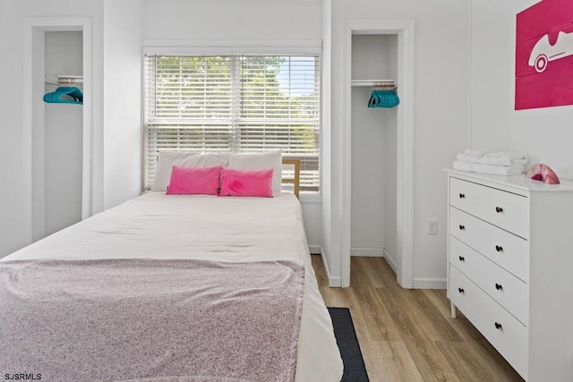 bedroom with light hardwood / wood-style flooring, multiple windows, and a closet