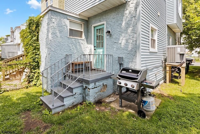 back of property featuring ac unit, central AC unit, and a lawn