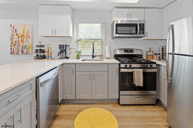 kitchen featuring white cabinets, stainless steel appliances, light hardwood / wood-style floors, and sink