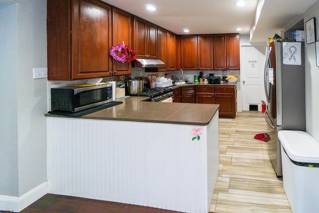 kitchen with kitchen peninsula, backsplash, and appliances with stainless steel finishes