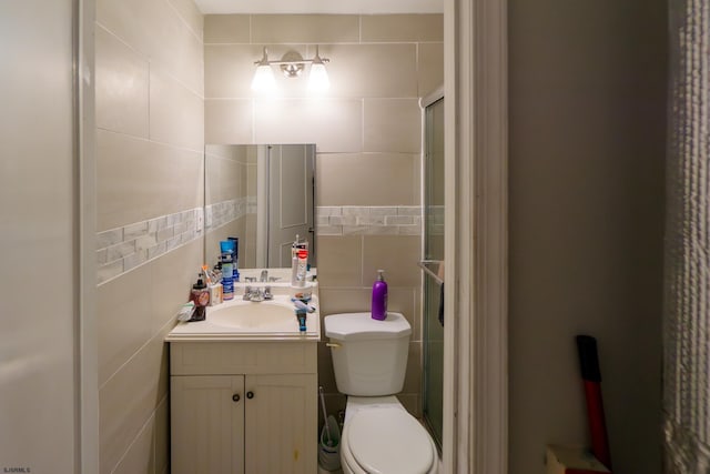 bathroom with vanity, an enclosed shower, tile walls, and toilet