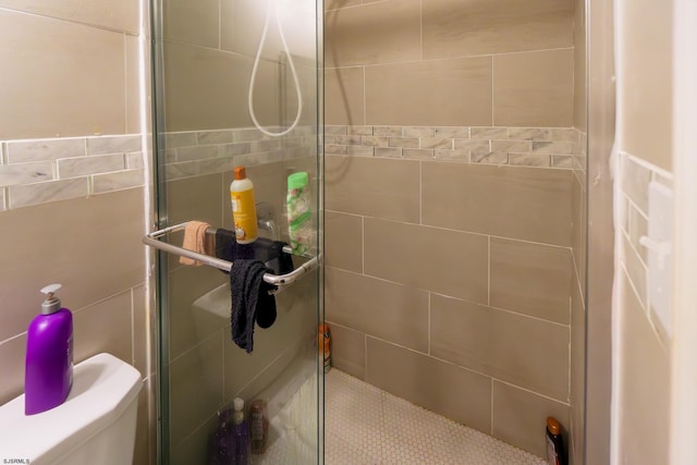 bathroom with toilet, an enclosed shower, and tile walls