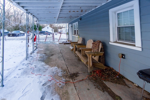 snow covered patio featuring a carport