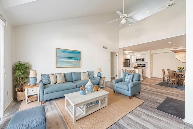 living room featuring light hardwood / wood-style floors, high vaulted ceiling, and ceiling fan