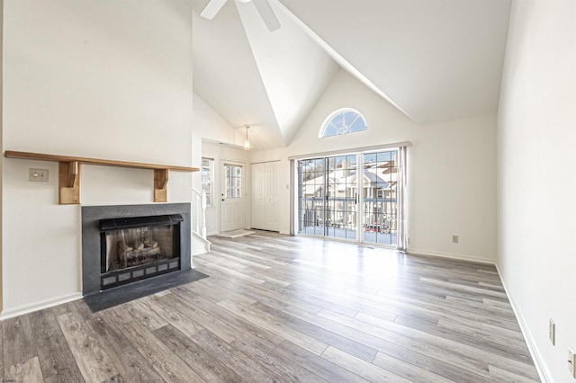 unfurnished living room featuring ceiling fan, a high ceiling, and light hardwood / wood-style flooring