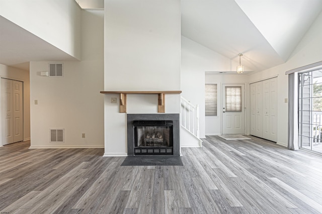 unfurnished living room featuring wood-type flooring and high vaulted ceiling