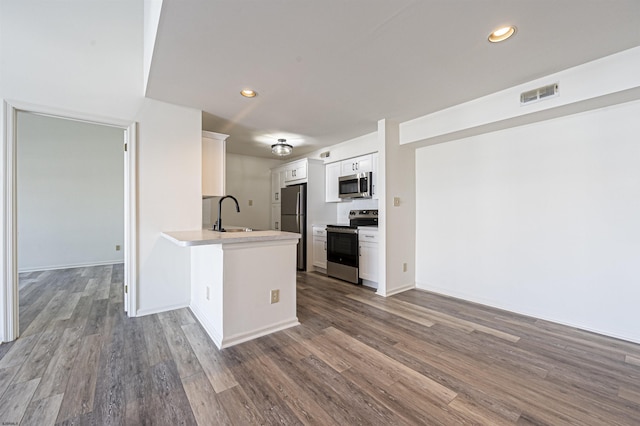 kitchen featuring kitchen peninsula, dark hardwood / wood-style flooring, stainless steel appliances, sink, and white cabinets