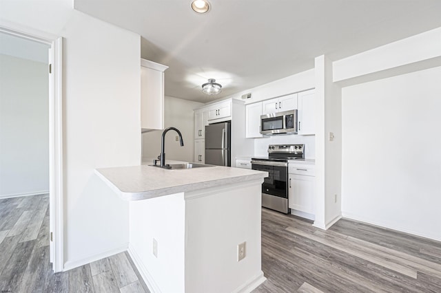 kitchen with white cabinets, appliances with stainless steel finishes, kitchen peninsula, and sink