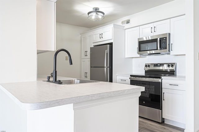 kitchen featuring white cabinetry, sink, stainless steel appliances, kitchen peninsula, and light wood-type flooring