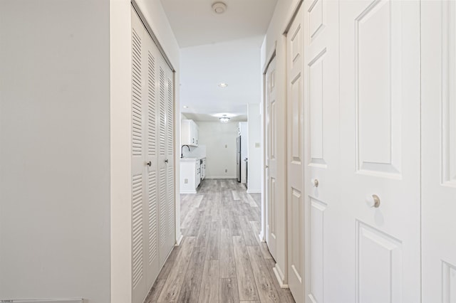 corridor with light hardwood / wood-style flooring and sink