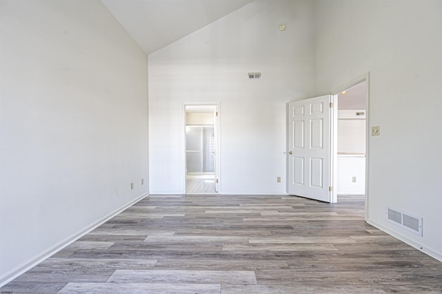 unfurnished room with high vaulted ceiling and light wood-type flooring