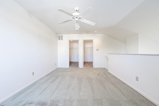 unfurnished bedroom with ceiling fan, a spacious closet, vaulted ceiling, and light carpet