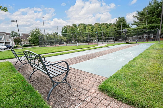 surrounding community with tennis court and a yard