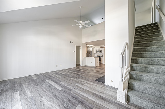 unfurnished living room with ceiling fan, hardwood / wood-style floors, and high vaulted ceiling