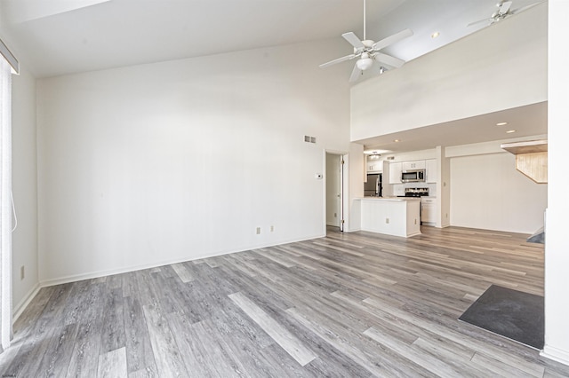 unfurnished living room featuring ceiling fan, high vaulted ceiling, and light wood-type flooring